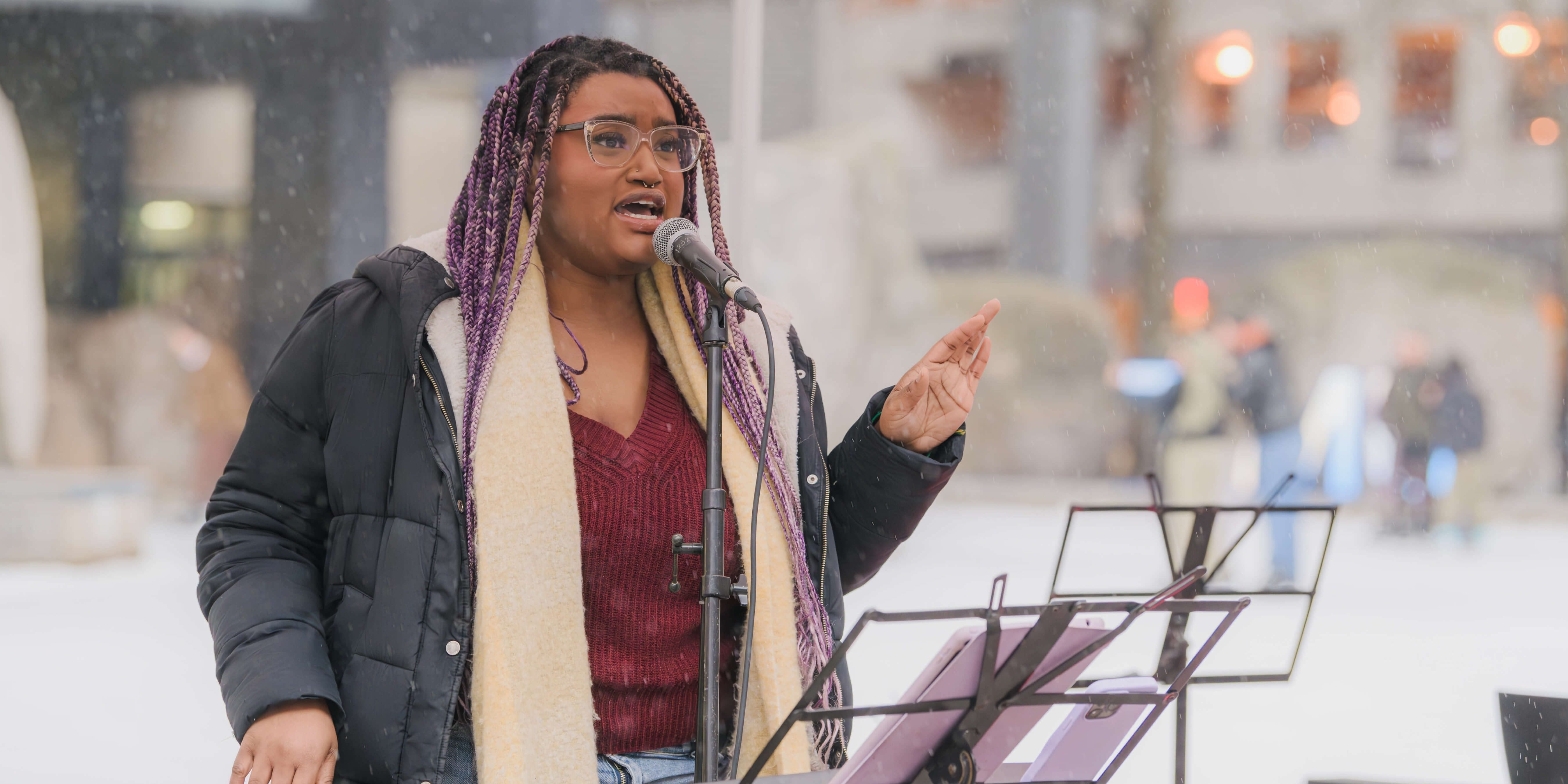 A student wearing a black coat singing at the TMU Frost Holiday Market.